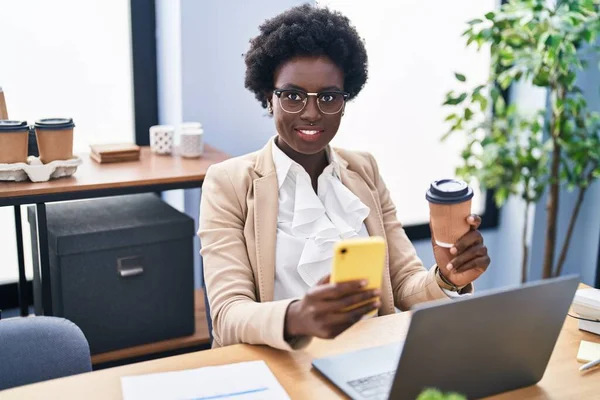 Genç Afrikalı Amerikalı iş kadını akıllı telefon kullanıyor ofiste kahve içiyor.