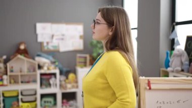 Young blonde woman preschool teacher smiling confident standing at kindergarten