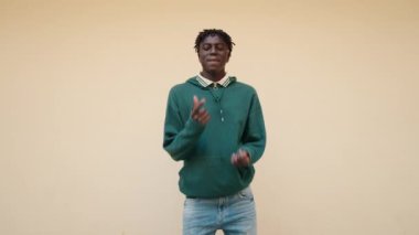 Afro-Amerikalı adam gülümsüyor, sokakta dans ediyor.