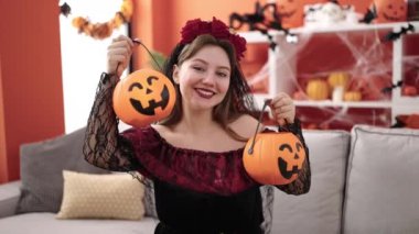 Young blonde woman wearing katrina costume holding halloween pumpkin baskets at home