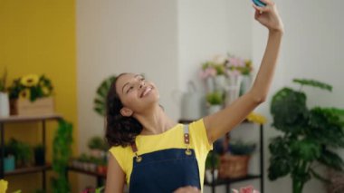 Genç Afrikalı Amerikalı kadın çiçekçi çiçekçide akıllı telefondan selfie çekiyor.