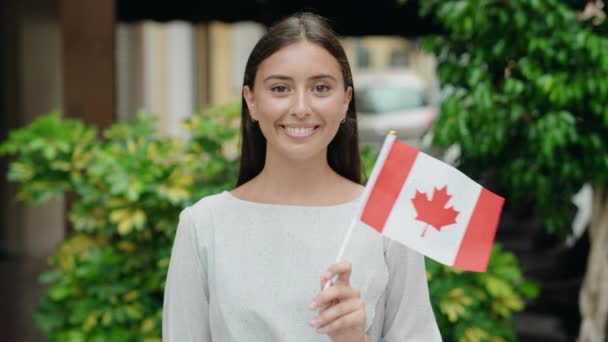 年轻美丽的惊慌失措的女人微笑着 自信地在街上举着加拿大国旗 — 图库视频影像