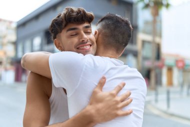 Two hispanic men couple smiling confident hugging each other at street