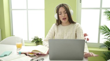Young beautiful hispanic woman student smiling confident listening to music at home