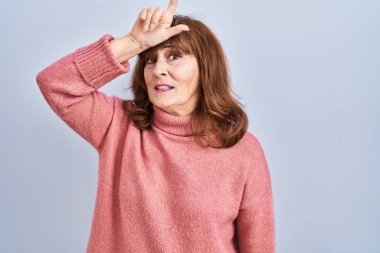 Orta yaşlı İspanyol bir kadın izole edilmiş arka planda duruyor. Alnında parmakları olan insanlarla alay ediyor. Ezik hareketler yapıyor, alay ediyor ve hakaret ediyor.. 