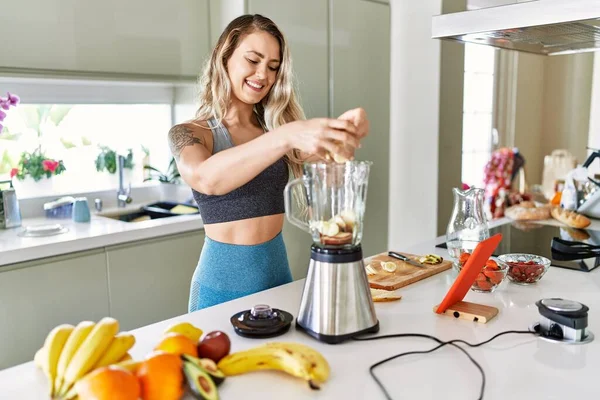 Young Woman Looking Online Juice Recipe Pouring Banana Blender Kitchen — Stok fotoğraf
