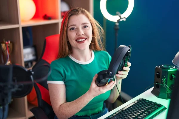 Young Redhead Woman Streamer Smiling Confident Holding Headphones Gaming Room — Foto de Stock