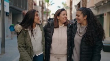 Anne ve kızları gülümseyerek sokakta kendinden emin konuşuyorlar.