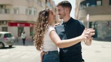 Young hispanic couple smiling confident hugging each other and dancing at street