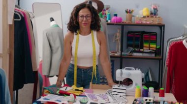 Middle age woman tailor smiling confident standing at clothing factory