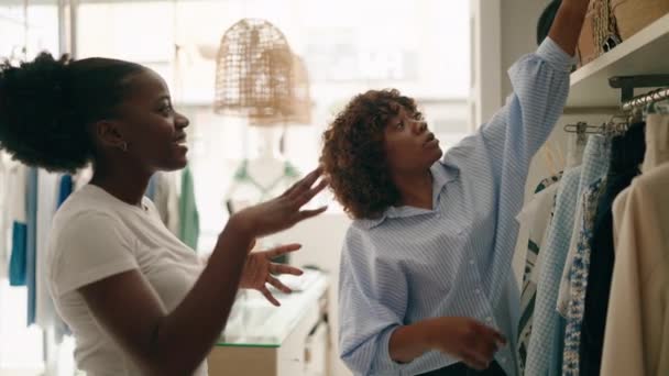 アフリカ系アメリカ人女性ショップアシスタントと顧客購入ハンドバッグで衣料品店 — ストック動画