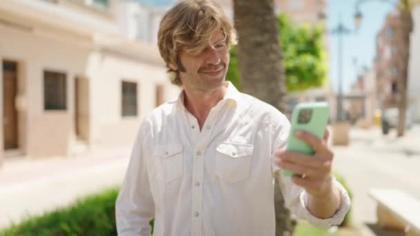 Hombre Joven Sonriendo Confiado Haciendo Selfie Por Teléfono Inteligente Parque — Vídeos de Stock