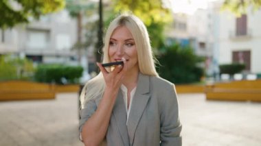 Young blonde woman executive talking on the smartphone at park