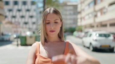 Genç ve güzel İspanyol kadın gülümsüyor. Kendine güveniyor. Sokakta elleriyle fotoğraf jesti yapıyor.