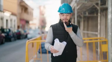 Young latin man worker with serious expression talking on the smartphone at street