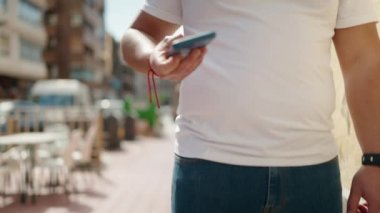 Genç Çinli adam gülümsüyor. Kendine güveni tam. Sokakta akıllı telefondan konuşuyor.