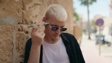 Genç beyaz adam gülümsüyor. Kendine güveniyor. Akıllı telefondan konuşuyor.