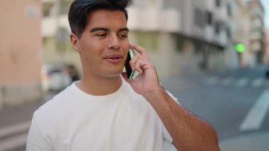 Genç İspanyol adam gülümsüyor. Kendine güveniyor. Sokakta akıllı telefondan konuşuyor.