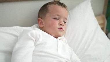 Adorable toddler lying on bed screaming at bedroom