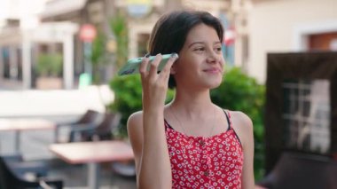 Sevimli İspanyol kız gülümsüyor. Caddedeki akıllı telefondan kendine güvenen sesli mesaj dinliyor.