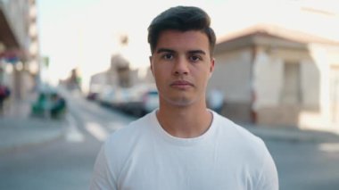 Young hispanic man wearing medical mask standing at street
