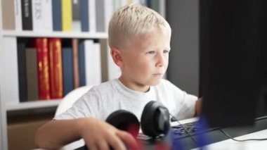 Adorable toddler student using computer writing on notebook at classroom