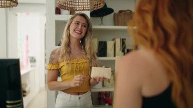 Two women customer buying purse at clothing store