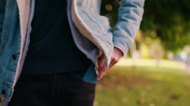 Genç İspanyol adam gülümsüyor. Parktaki akıllı telefondan konuşuyor.