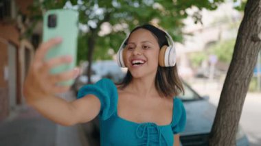Young hispanic woman smiling confident having video call at street