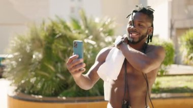 African american woman shirtless smiling confident having video call at park