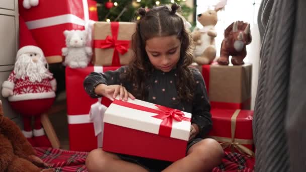 Adorable Hispanic Girl Unpacking Gift Sitting Floor Christmas Tree Home — Stockvideo