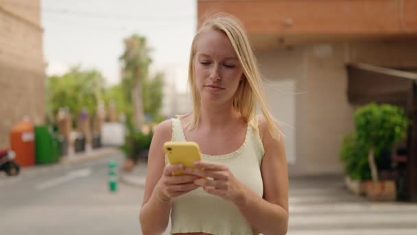 Junge Blonde Frau Nutzt Smartphone Mit Entspanntem Gesichtsausdruck Auf Der — Stockvideo