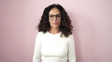 Middle age hispanic woman smiling confident standing with arms crossed gesture over isolated pink background