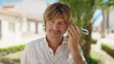 Young man listening audio message by the smartphone at park