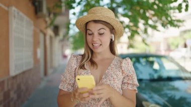 Yaz şapkası takan genç bir turist sokakta müzik dinliyor.