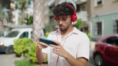 Young arab man smiling confident playing video game at street