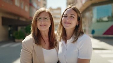 Anne ve kızı gülümsüyor, sokakta birbirlerine sarılıyorlar.