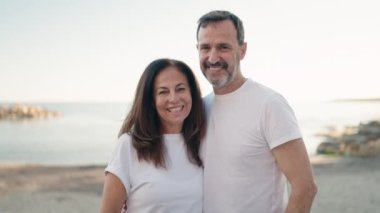 Erkek ve kadın çift sahilde birbirlerine sarılıyorlar.