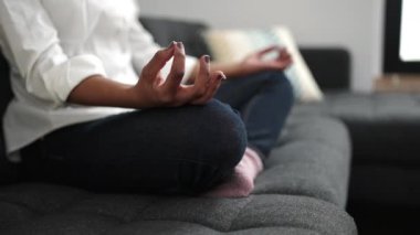 African american woman doing yoga exercise sitting on sofa at home