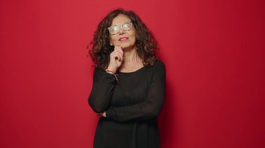 Middle age woman smiling confident standing over red background