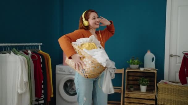 Young Redhead Woman Listening Music Holding Basket Clothes Laundry Room — Wideo stockowe