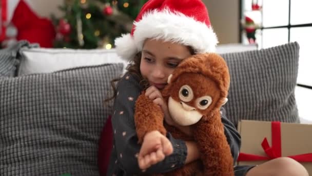 Adorable Hispanic Girl Hugging Monkey Doll Sitting Sofa Christmas Tree — Vídeos de Stock