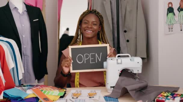 在裁缝店 非洲裔美国妇女裁缝坐在桌子上 手里拿着敞开的黑板信息 — 图库视频影像