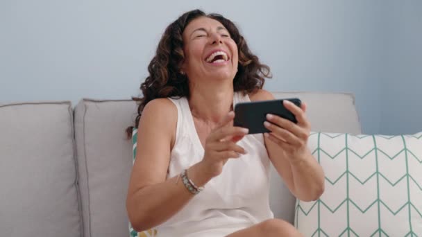 Μέση Ηλικία Γυναίκα Βλέποντας Βίντεο Στο Smartphone Κάθεται Στον Καναπέ — Αρχείο Βίντεο