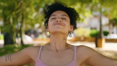 Young hispanic woman smiling confident breathing at park