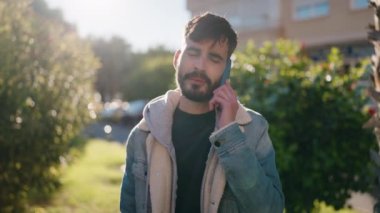 Genç İspanyol adam gülümsüyor. Parktaki akıllı telefondan konuşuyor.