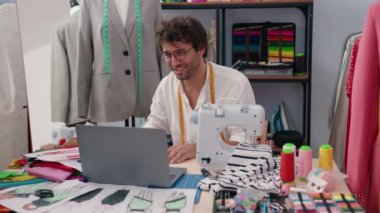 Young hispanic man tailor smiling confident having video call at clothing factory