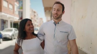 Man and woman interracial couple hugging each other walking at street