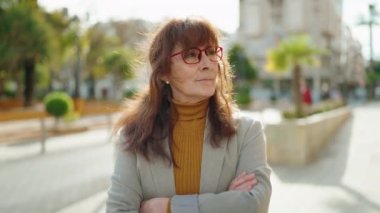 Middle age woman business executive standing with arms crossed gesture at park