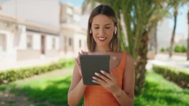 Genç, güzel, İspanyol bir kadın, gülümsüyor. Parktaki dokunmatik evde videolar izliyor.